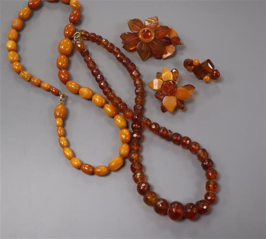 A single strand graduated oval amber bead necklace, gross 22 grams, 44cm, one other amber necklace and two brooches.